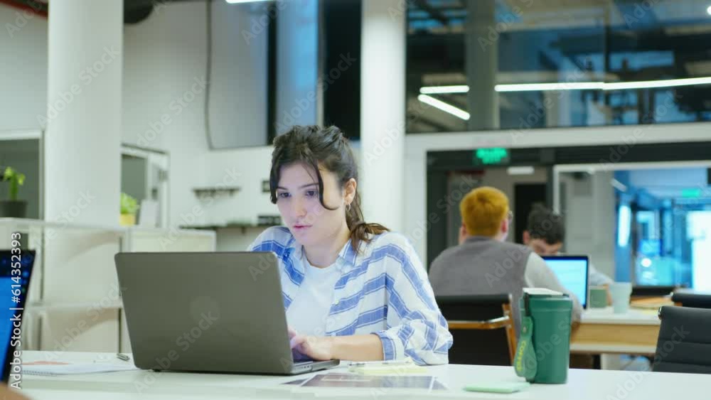 custom made wallpaper toronto digitalYoung concentrated gen Z girl in casual wear sitting at desk with coffee tumbler, using laptop, working in the office. Medium handheld shot