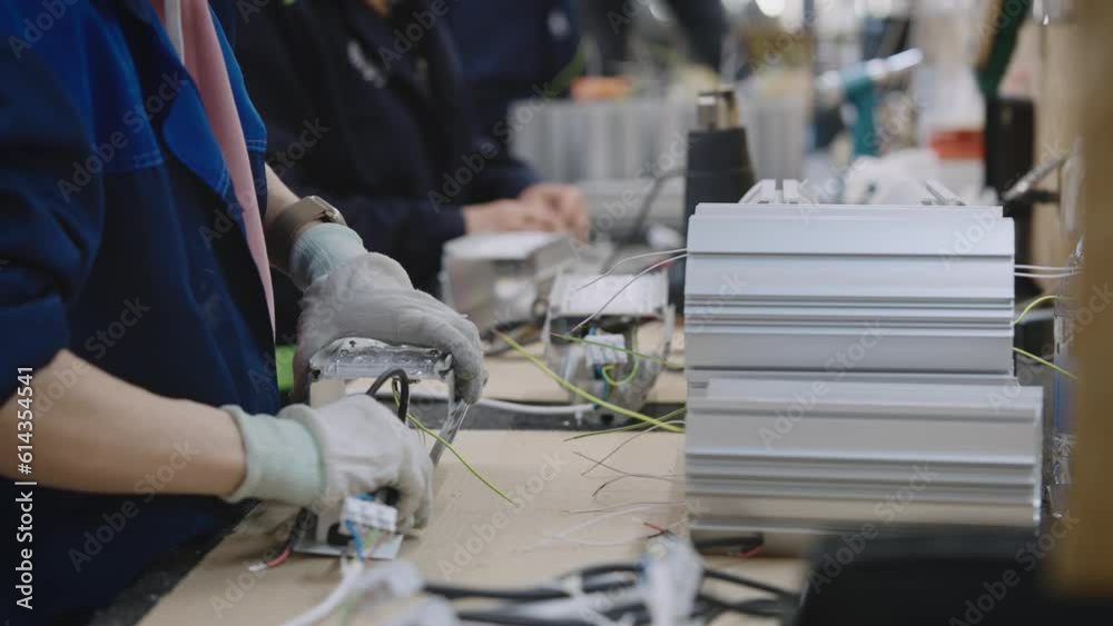 Close-up of a lighting factory. A worker manually assembles an electric industrial lamp.