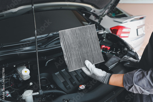 Auto mechanic checking, cleaning and replacing car air filter. Concept of car care service maintenance. © Jintana