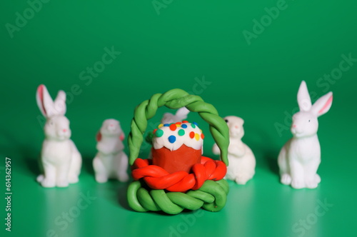 Figures of toy rabbits and Easter cake on a green background.