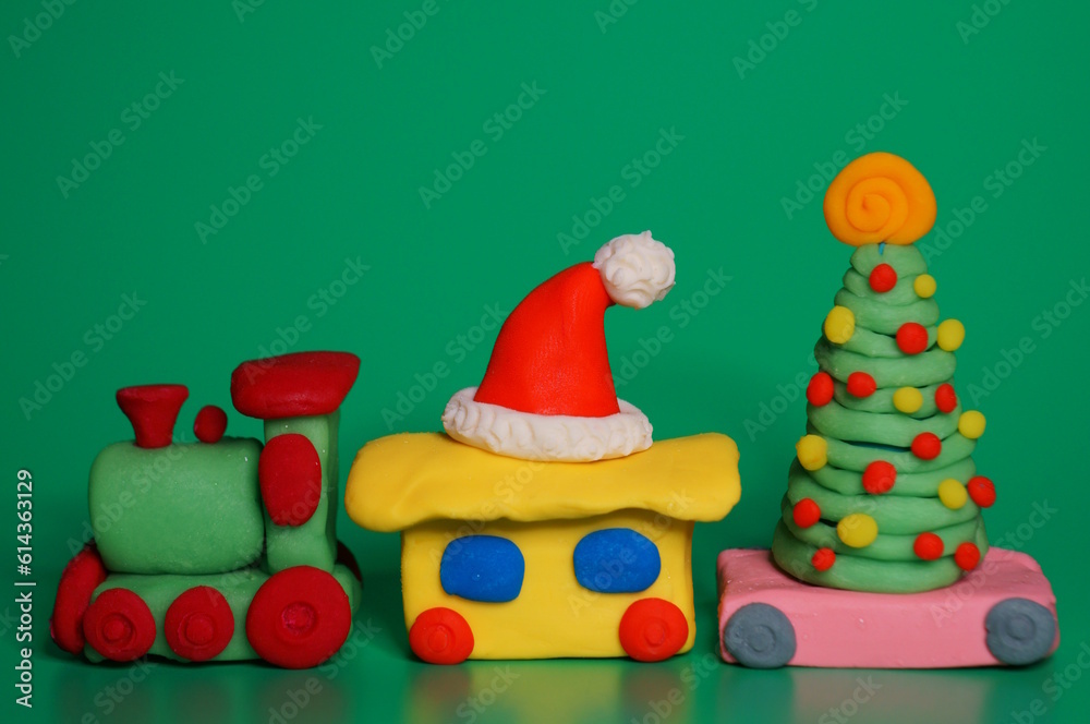 A toy train with a Christmas tree and a Santa Claus hat. Christmas decorations. Green background. A toy train with a Christmas tree and a Santa Claus hat. Christmas decorations. Green background.