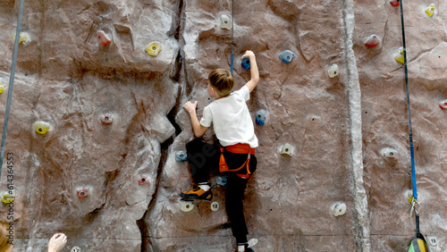 Fototapeta Naklejka Na Ścianę i Meble -  the boy on the climbing wall goes up