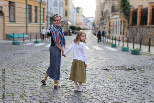 Grandmother and granddaughter walking around the city, turned back on the paving stones. © Andrii Zastrozhnov