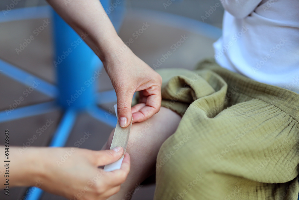 Close-up, sticking a band-aid on a child's leg wound.