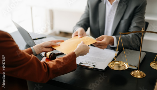 justice and law concept.passing bribe money in the envelop at lawyer office. businessman hand taking bribe money from male