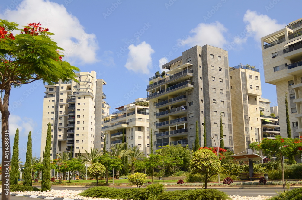 Obraz premium Modern residential area. Flowering trees near the new building. Luxury real estate. Investment in an apartment. Comfortable balconies and blooming Royal poinciana