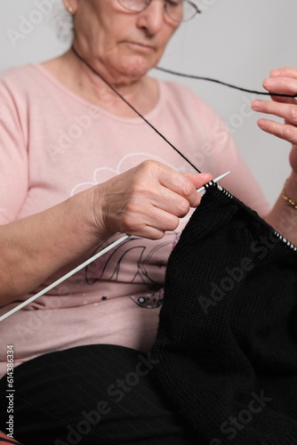 old woman spends time alone at home and knitting photo