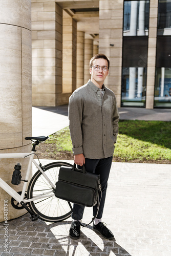 A young hipster man has arrived and is getting a job in the office. The guy with the business bag is standing tall.