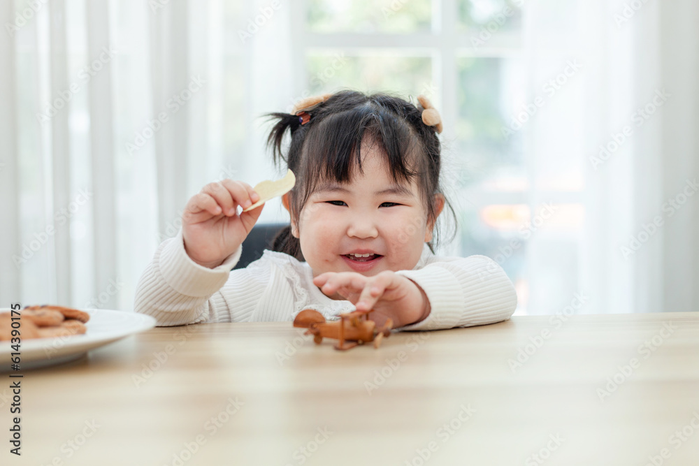 Cute little Asian girl eats breakfast with milk at the breakfast table. The concept of young children eating food. Cute little Asian girl eats breakfast with milk at the breakfast table. The concept of young children eating food.
