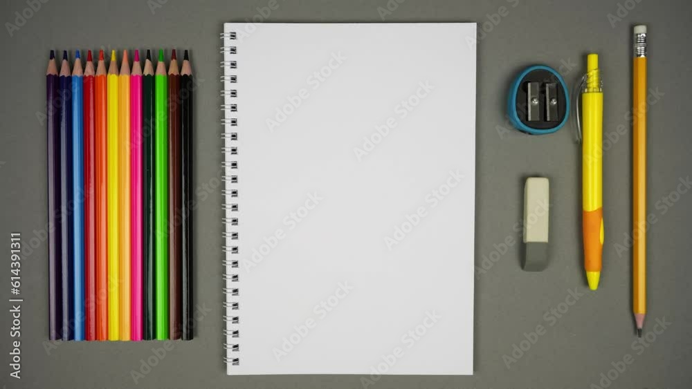 Top view of Blank Spiral Notebook With Color Pencils On Grey Background. Colored school supplies. Stop Motion