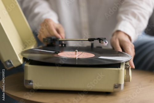 Classical music lover playing vinyl record, close up view. Female hands put plastic disc on turntable to enjoy sound from past, retro music lover relish pastime with favourite melody alone at home