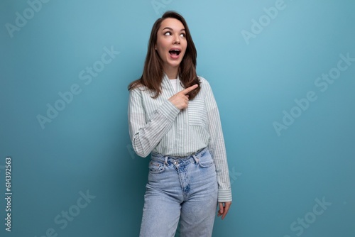 young brunette lady dressed in a striped shirt and jeans points her finger to the side