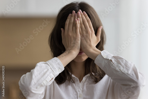 Cuadro en lienzo Close up head shot portrait young woman hides her face behind palms feels ashamed, shy or afraid pose indoor