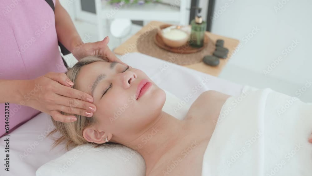 Young woman having facial massage by masseuse at spa salon. Spa for relaxation in modern wellness center. Young woman having facial massage by masseuse at spa salon. Spa for relaxation in modern wellness center.
