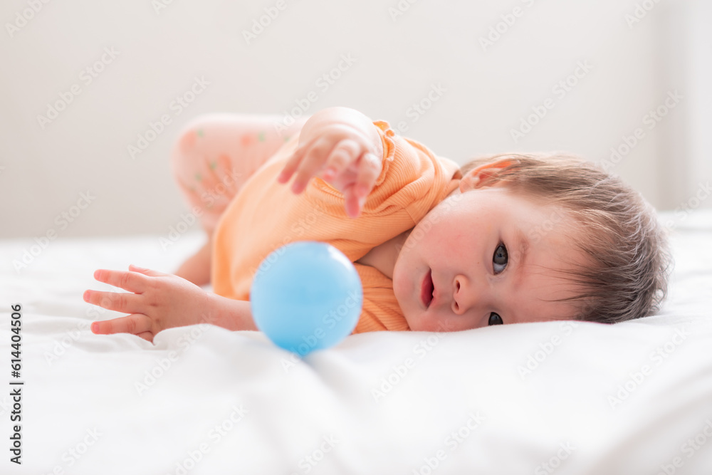 lifestyle home portrait of happy and beautiful 8 months old baby girl mixed race Asian Caucasian playing with ball cheerful on bed and exploring the surroundings curious lifestyle home portrait of happy and beautiful 8 months old baby girl mixed race Asian Caucasian playing with ball cheerful on bed and exploring the surroundings curious