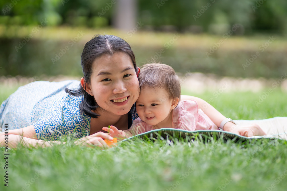 outdoors lifestyle portrait of mother and daughter - young happy and sweet Asian Korean woman playing with her 8 months baby girl on grass at city park outdoors lifestyle portrait of mother and daughter - young happy and sweet Asian Korean woman playing with her 8 months baby girl on grass at city park