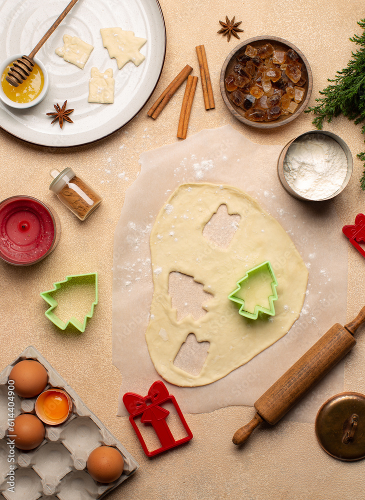 Process of making Christmas cookies with homemade dough,cookie cutters in the shape of tree and gift box,rolling pin,flour,cinnamon,cocoa powder and fresh eggs on beige table.Top view. Process of making Christmas cookies with homemade dough,cookie cutters in the shape of tree and gift box,rolling pin,flour,cinnamon,cocoa powder and fresh eggs on beige table.Top view.