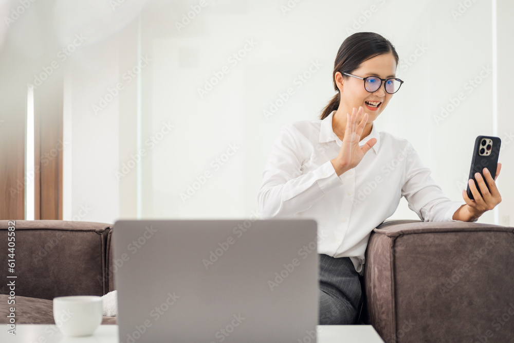 Woman waving on video call through smart phone at home Woman waving on video call through smart phone at home