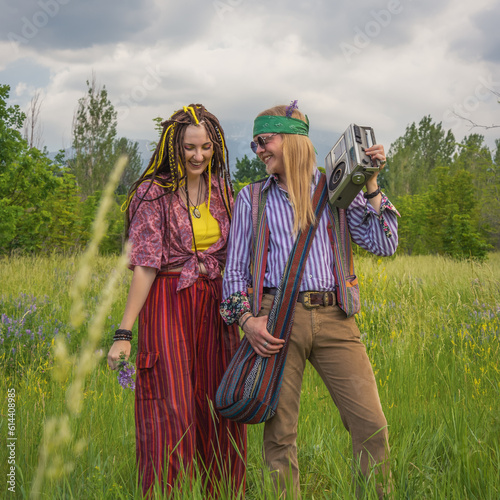 Hippie guy and girl listen to music on a vintage cassette recorder in a forest clearing