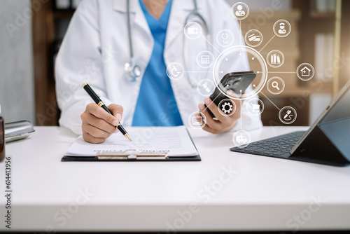Physician or practitioner in room writing on blank notebook and work on laptop computer, smartphone on the desk,  Medic tech concept. photo