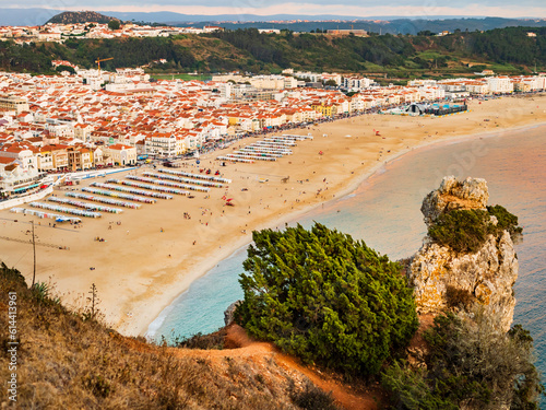 Amazing view of Nazare beach (praia de Nazare) with colorful bathing huts and cityscape of the village in background, Portugal 