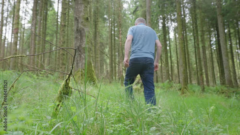 Older man walks through forest, looks around and then holds his arms high Older man walks through forest, looks around and then holds his arms high