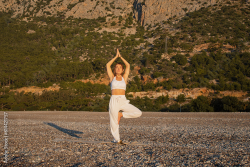 of a girl doing yoga on the background of mountains and forest