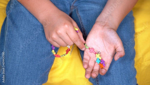 boy child hands hold christian cattolic  rosary making a prayer - religion and faith in young millenials - colorful cross in hand - Lgbt gay pride symbol  photo