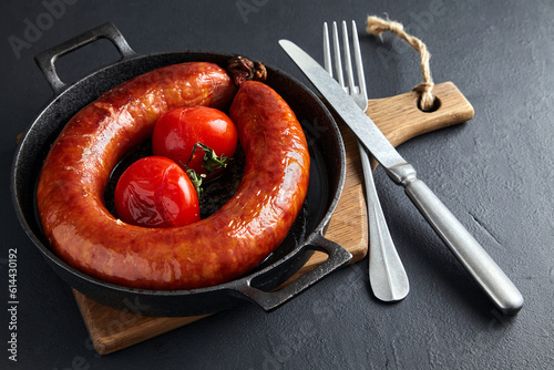 fried meat sausage in a cast iron skillet with tomatoes and cutl photo