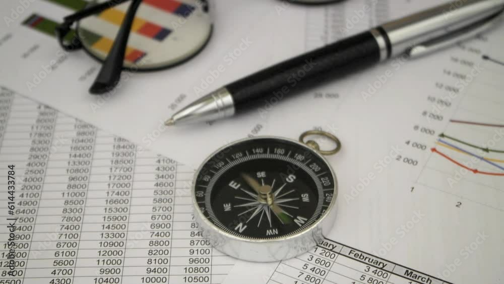 Turbulence in financial word concept. Spinning compass on financial reports with pen and glasses. Turbulence in financial word concept. Spinning compass on financial reports with pen and glasses.
