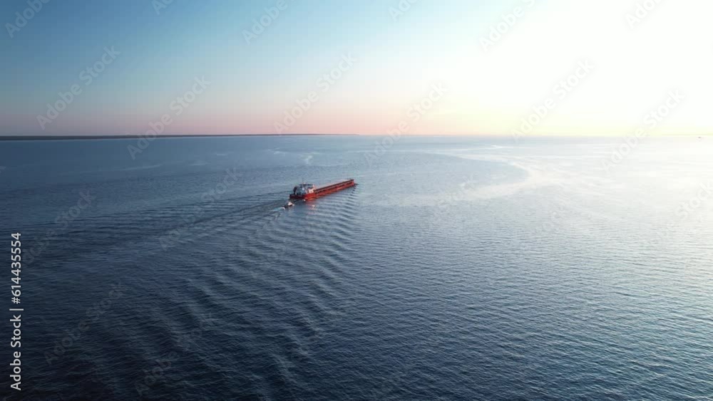 Aerial shot of a cargo ship in the open blue sea - top down view, the concept of export-import freight transport, a container ship transports goods by sea.