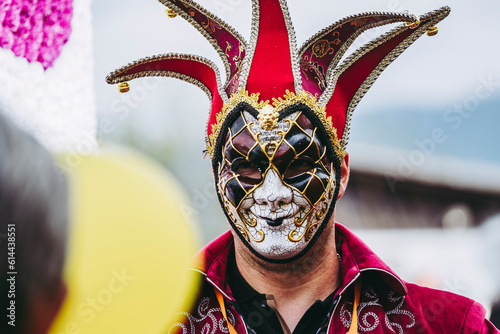 Homme qui porte un masque de carnaval coloré rouge noir blanc doré