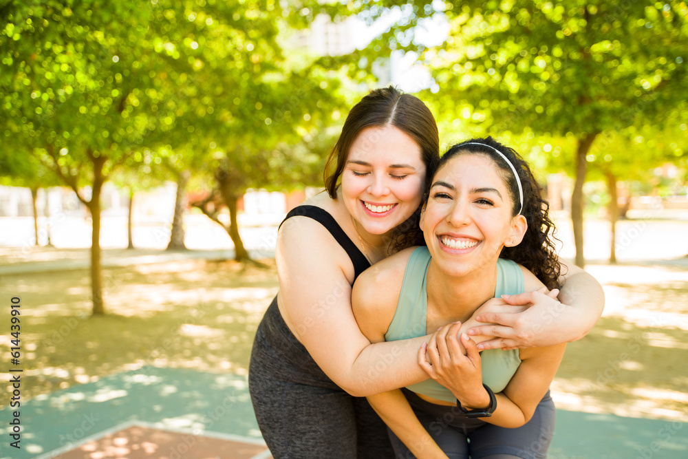 Naklejka premium Attractive women friends hugging after running outdoors