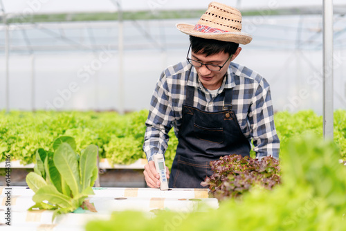 Agribusiness farmer and hydroponic farming concept, Man using pH meter to testing and control water system of hydroponics farm for salad vegetables plantation in greenhouse