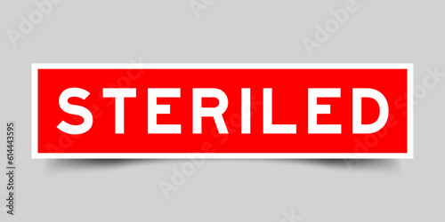 Red color square shape sticker label with word steriled on gray background