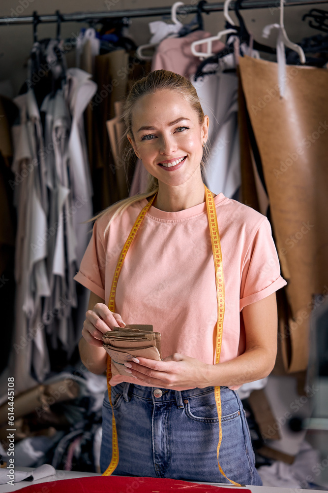 attractive caucasian dressmaker woman sews clothes at tailor office, engaged in tailoring, blonde female in casual wear posing at camera, holding fabric in hands. dressmaking industry