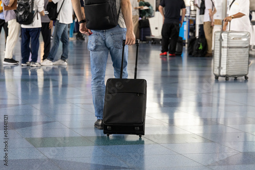 空港でスーツケースをひいて歩く男性の後ろ姿