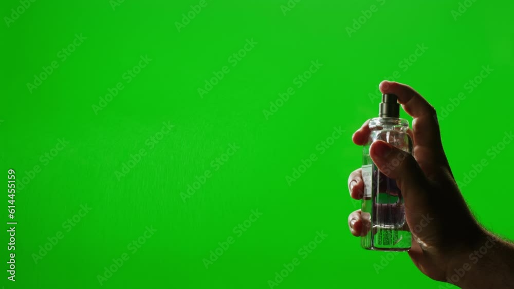Young man applying perfume to skin on chroma key green screen, close up of spraying deodorant luxury perfume.