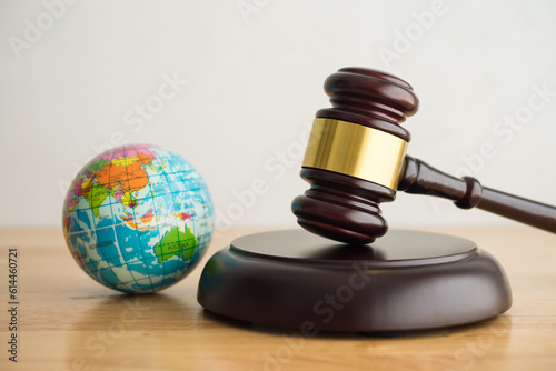 Hammer judge gavel and world globe in courtroom with white wall background. World court, International Court of Justice (ICJ) concept. World court adjudicates general disputes between countries.