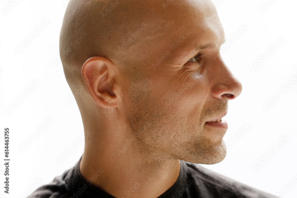 Fototapeta premium A profile portrait of a bald man half smiling