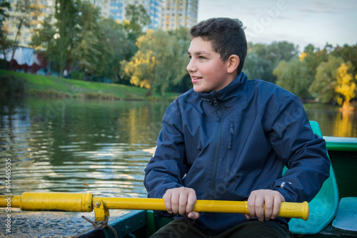 A boy is sailing in a boat in the autumn park.