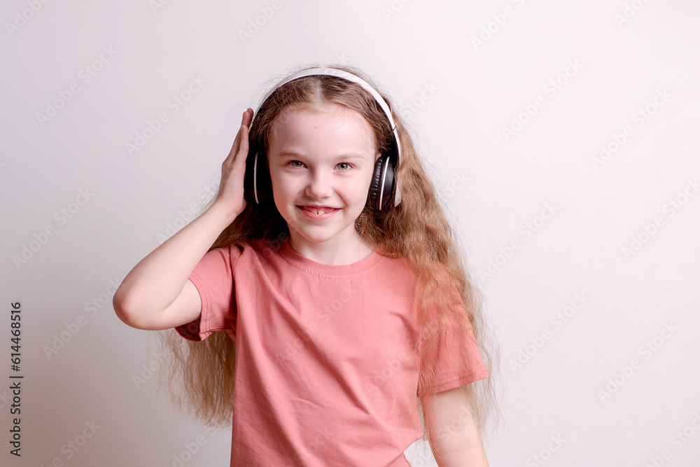 Cheerful happy girl with long hair dancing to music, listening to songs in headphones on a white background Cheerful happy girl with long hair dancing to music, listening to songs in headphones on a white background