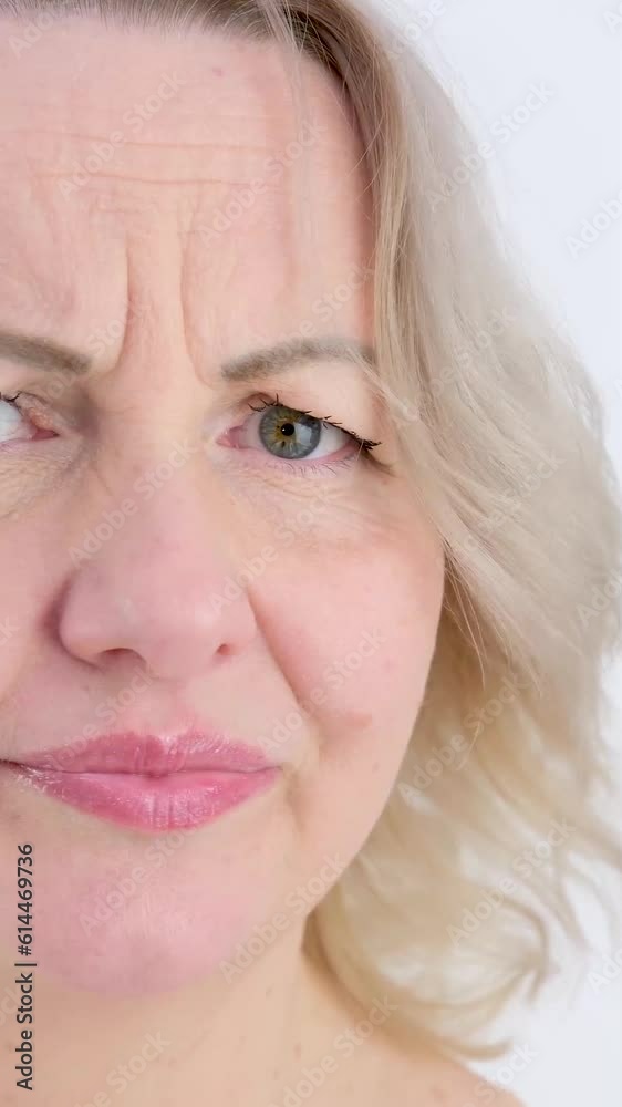 Photo of thoughtful woman bites lower lip, looks with dreamy expression aside, wearing stylish beige hoodie, stands against white wall. Copy space for your text. High quality photo Photo of thoughtful woman bites lower lip, looks with dreamy expression aside, wearing stylish beige hoodie, stands against white wall. Copy space for your text. High quality photo