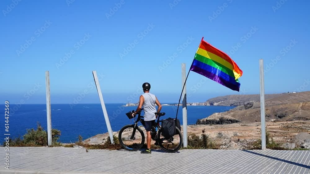 Gay boy with the rainbow flag on the bicycle in Gran Canaria Gay boy with the rainbow flag on the bicycle in Gran Canaria