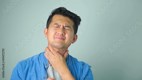 Cuadro en lienzo Sick asian man with sore throat on white background...