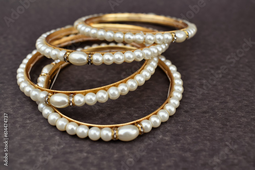 A closeup selective focus picture of a Gold bangles with Pearls .