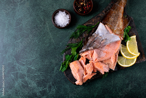 Hot smoked trout fillet on dark green table. Top view. Mockup with copy space