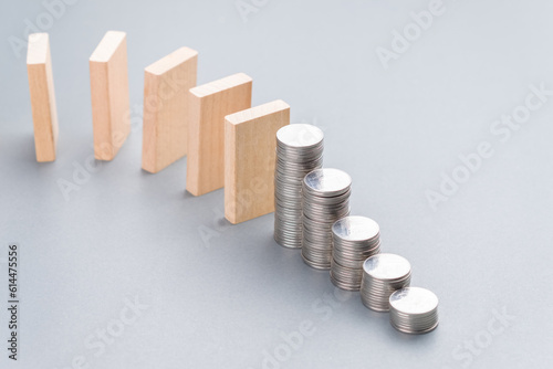 Wooden domino and descending heap coins stairs, financial plan in ecomonic crisis