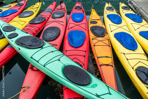 Yellow, orange and red kayaks floating in a tight formation and one green kayak laid across, Valdez Harbor, Alaska. photo
