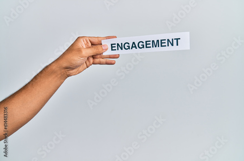 Hand of caucasian man holding paper with engagement word over isolated white background